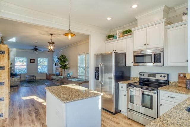 kitchen with light stone counters, decorative light fixtures, appliances with stainless steel finishes, white cabinets, and a kitchen island