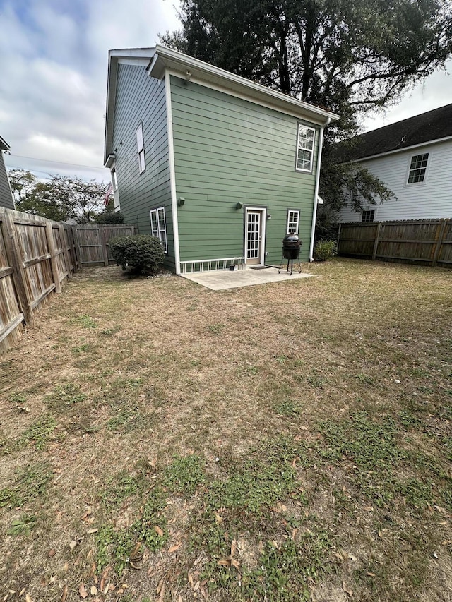 rear view of house featuring a fenced backyard, a lawn, and a patio