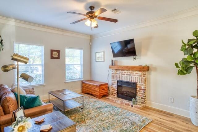 living room featuring a fireplace, visible vents, ornamental molding, wood finished floors, and baseboards