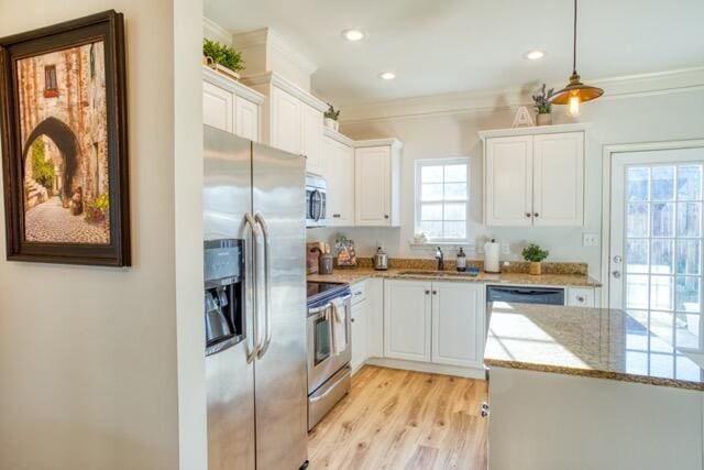 kitchen with light stone counters, crown molding, stainless steel appliances, white cabinets, and a sink