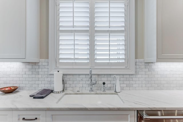 room details featuring white cabinets, light stone counters, and sink