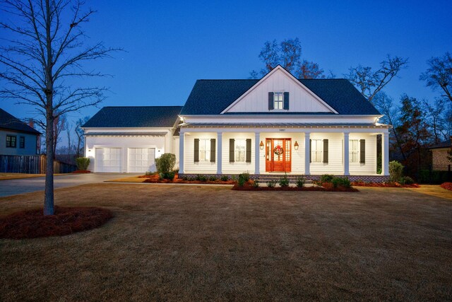 view of front of house featuring covered porch, a front yard, and a garage