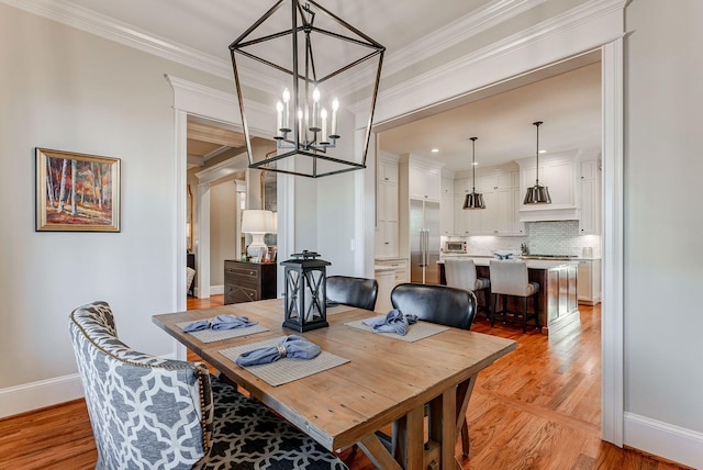 dining space featuring crown molding, a notable chandelier, and light wood-type flooring