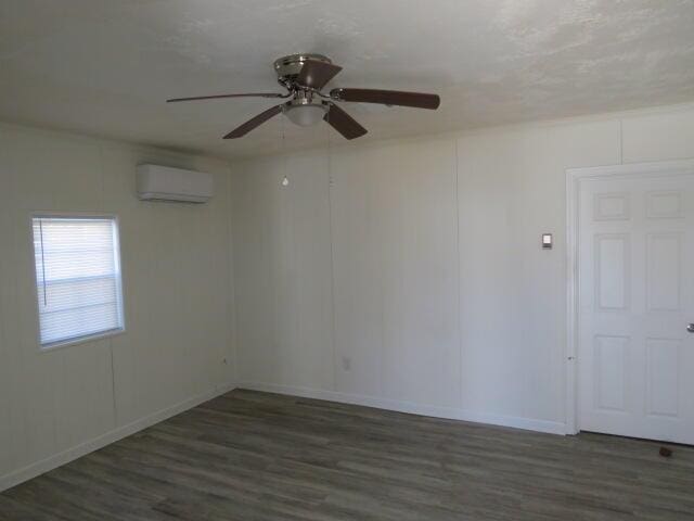 spare room featuring a ceiling fan, wood finished floors, and a wall mounted AC