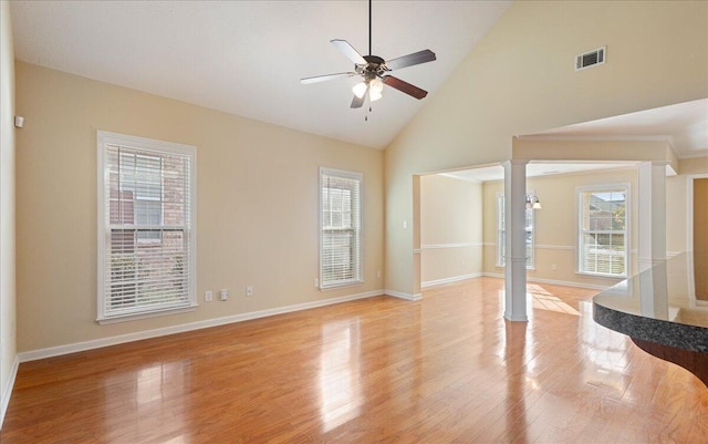 unfurnished living room with ceiling fan, ornate columns, high vaulted ceiling, and light hardwood / wood-style flooring