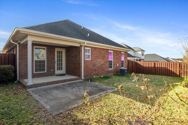 rear view of house with a lawn, central AC unit, and a patio area