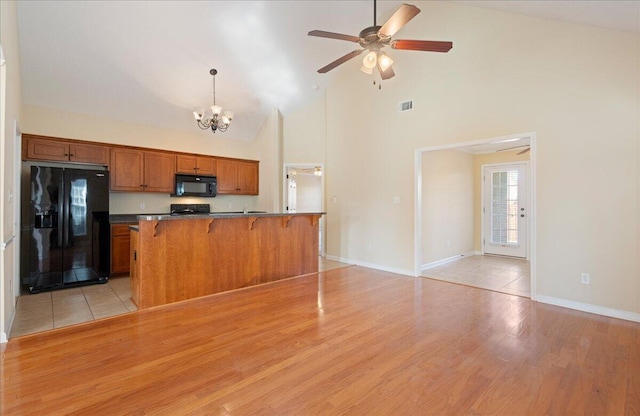 kitchen with black appliances, a breakfast bar, ceiling fan with notable chandelier, and decorative light fixtures