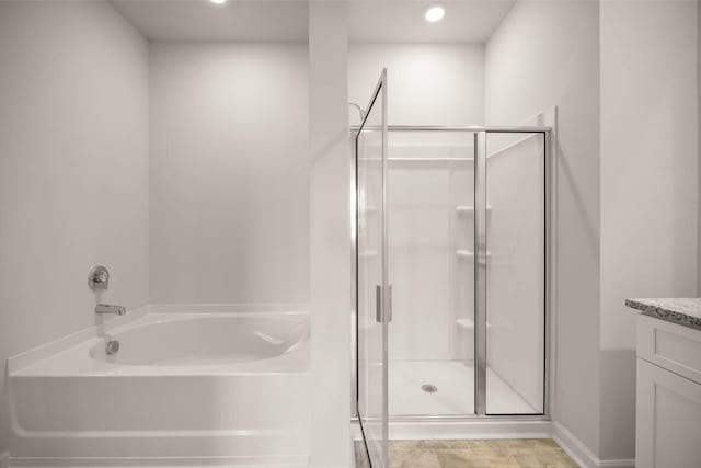 bathroom with baseboards, a garden tub, a shower stall, and vanity