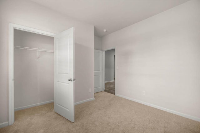 unfurnished bedroom featuring a closet, baseboards, and carpet flooring