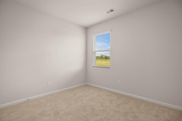 spare room with light colored carpet, visible vents, and baseboards