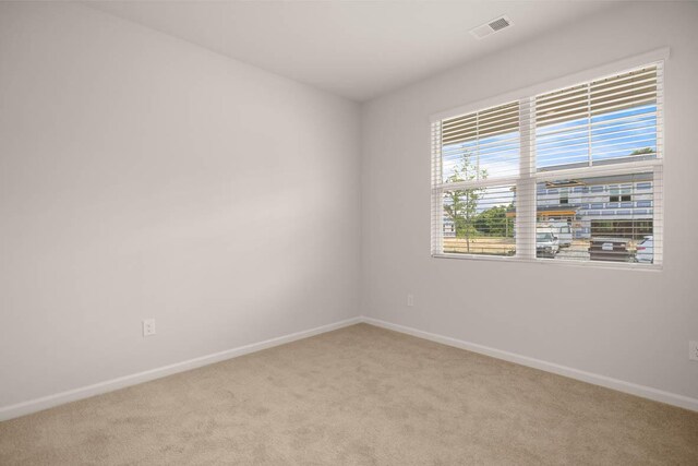 carpeted empty room featuring baseboards and visible vents