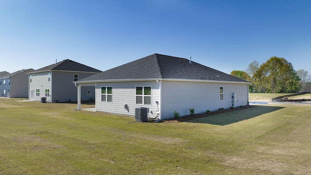 rear view of property featuring central air condition unit and a lawn