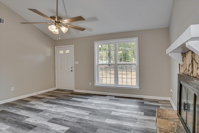 unfurnished living room featuring ceiling fan, a stone fireplace, wood-type flooring, and vaulted ceiling