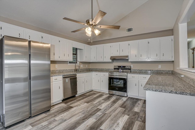 kitchen featuring sink, vaulted ceiling, light stone countertops, white cabinetry, and stainless steel appliances