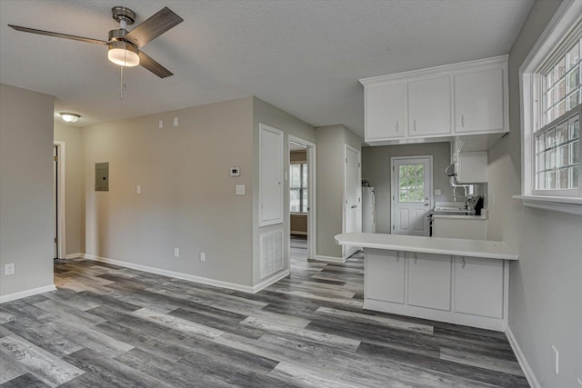 kitchen featuring a breakfast bar, white cabinets, ceiling fan, a textured ceiling, and kitchen peninsula