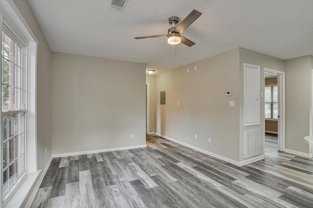 empty room featuring hardwood / wood-style floors, ceiling fan, a textured ceiling, and electric panel