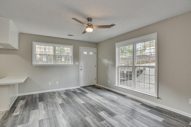 interior space featuring ceiling fan, wood-type flooring, and a textured ceiling