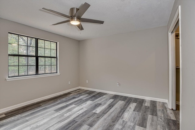 empty room with hardwood / wood-style floors, ceiling fan, and a textured ceiling