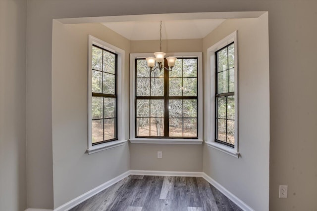 unfurnished dining area with an inviting chandelier and dark wood-type flooring