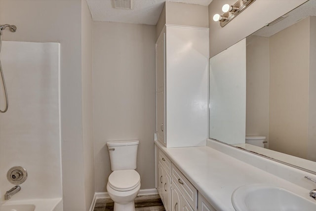 full bathroom with vanity, a textured ceiling, wood-type flooring, washtub / shower combination, and toilet