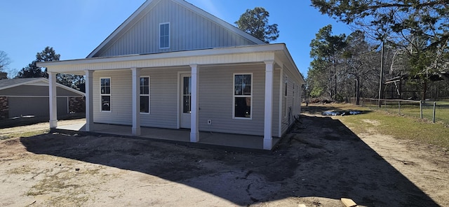 rear view of house with fence, a porch, and board and batten siding