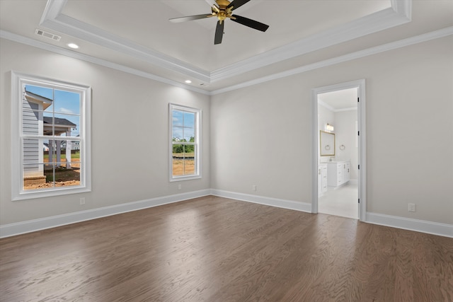 empty room with a raised ceiling, dark wood-style floors, ornamental molding, a ceiling fan, and baseboards