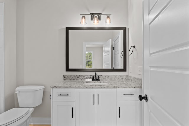 bathroom featuring toilet, vanity, and baseboards