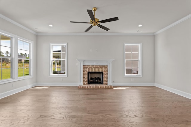 unfurnished living room with wood finished floors, baseboards, crown molding, a ceiling fan, and a brick fireplace