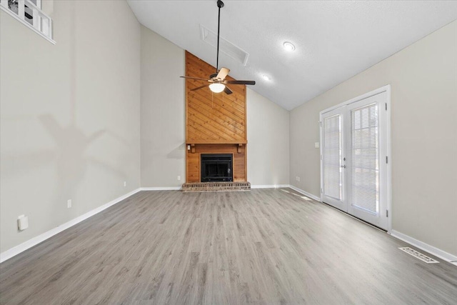 unfurnished living room featuring ceiling fan, hardwood / wood-style floors, high vaulted ceiling, a fireplace, and a textured ceiling