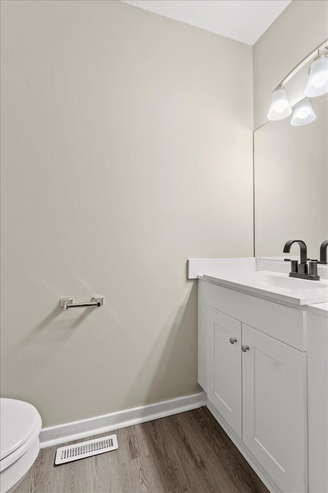 bathroom with vanity, hardwood / wood-style floors, and toilet