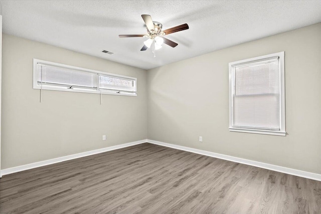 spare room featuring dark wood-type flooring, ceiling fan, and a textured ceiling