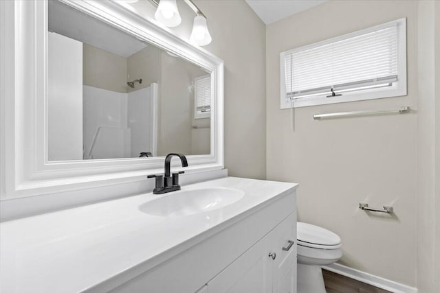 bathroom with hardwood / wood-style flooring, vanity, a shower, and toilet