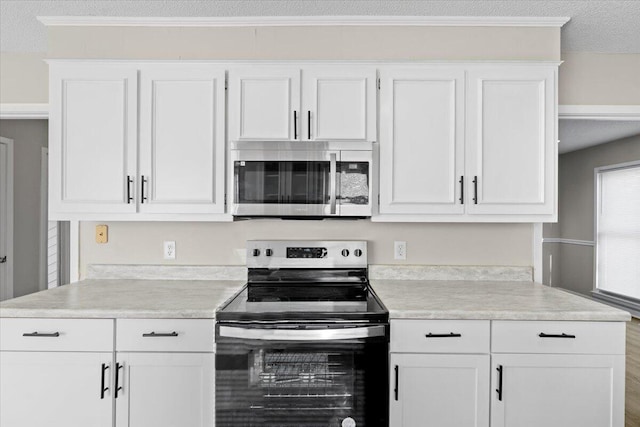 kitchen with appliances with stainless steel finishes, a textured ceiling, and white cabinets