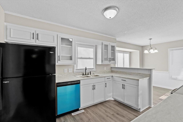 kitchen with sink, black fridge, white cabinetry, hanging light fixtures, and dishwashing machine