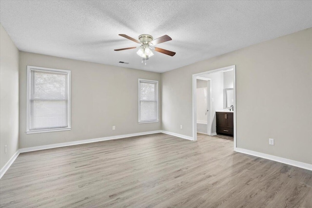 unfurnished room featuring ceiling fan, light hardwood / wood-style floors, a textured ceiling, and a wealth of natural light