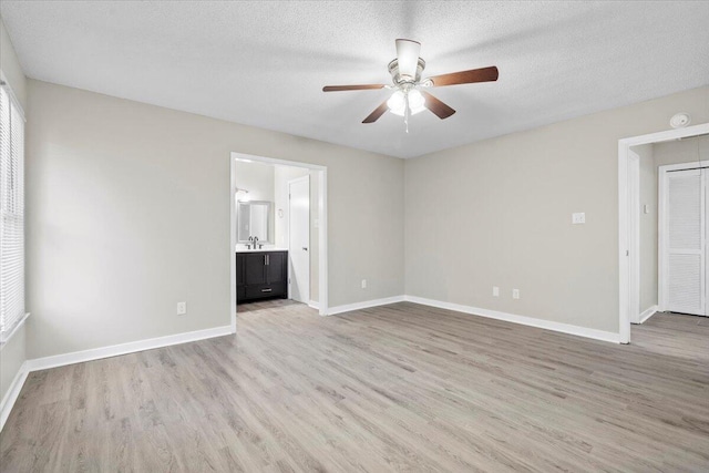 spare room with ceiling fan, sink, a textured ceiling, and light wood-type flooring