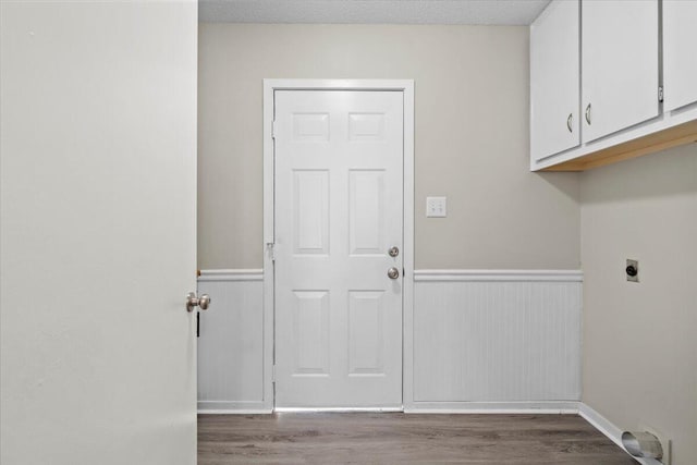 clothes washing area with cabinets, wood-type flooring, electric dryer hookup, and a textured ceiling