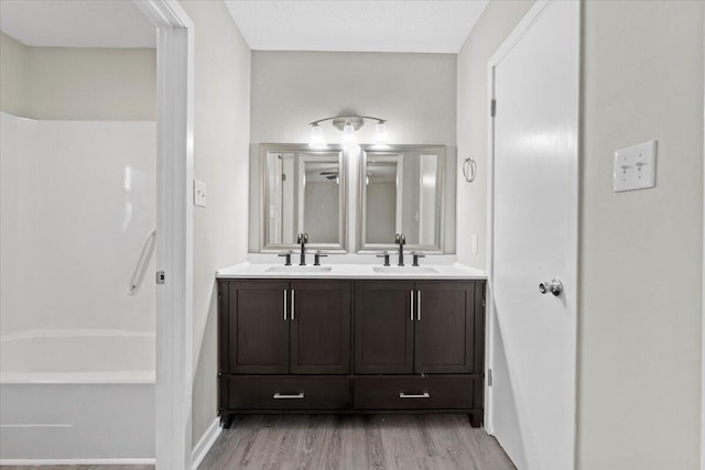 bathroom with vanity, hardwood / wood-style floors,  shower combination, and a textured ceiling