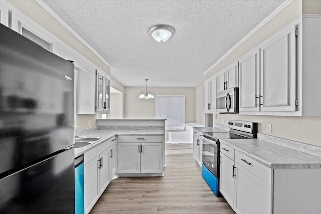 kitchen featuring white cabinetry, sink, hanging light fixtures, stainless steel appliances, and a textured ceiling