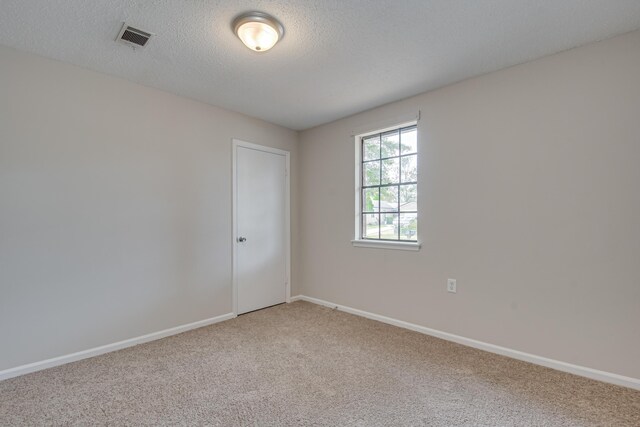 spare room with a textured ceiling and light carpet