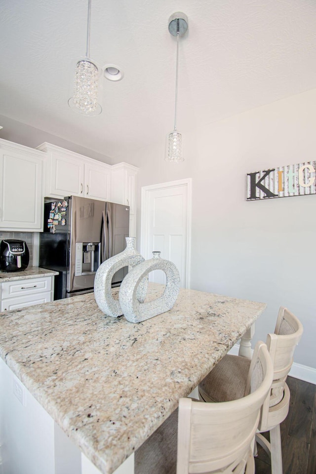 1144 Bubbling Springs Dr, Graniteville, SC 29829 - kitchen featuring light stone counters, a center island, white cabinetry, stainless steel fridge with ice dispenser, and dark wood-style flooring