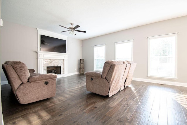 living room with a fireplace, dark hardwood / wood-style flooring, and ceiling fan