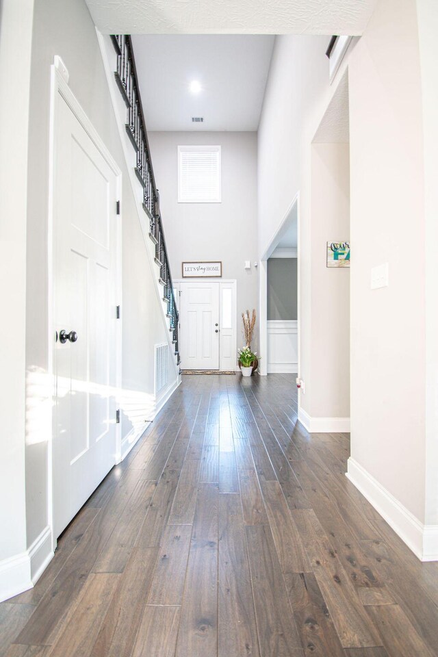 entryway with dark hardwood / wood-style flooring and a towering ceiling