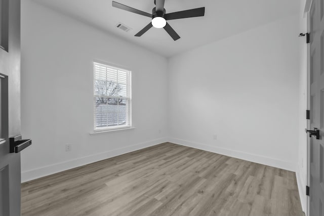 spare room with light wood finished floors, baseboards, visible vents, and a ceiling fan