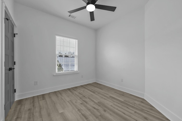 spare room featuring baseboards, ceiling fan, visible vents, and light wood-style floors