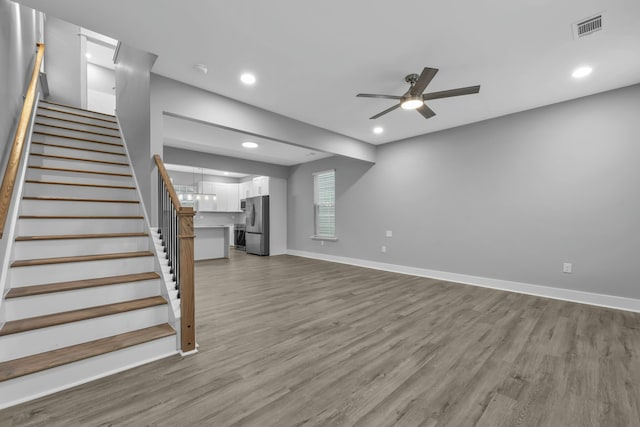 unfurnished living room featuring recessed lighting, stairway, light wood-style floors, a ceiling fan, and baseboards