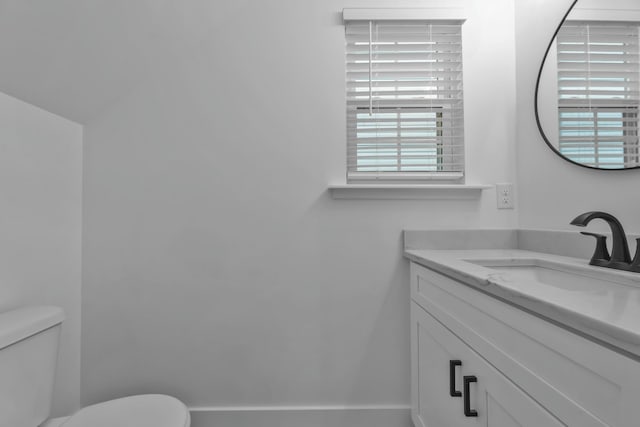 bathroom with baseboards, vanity, and toilet