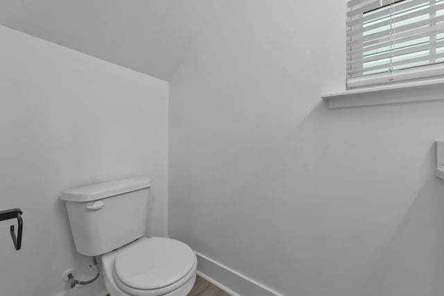 half bath featuring toilet and baseboards