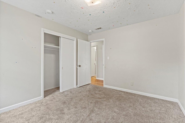 unfurnished bedroom with visible vents, a closet, baseboards, a textured ceiling, and carpet