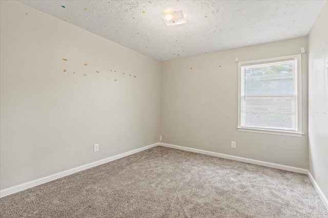 empty room featuring baseboards, carpet flooring, and a textured ceiling